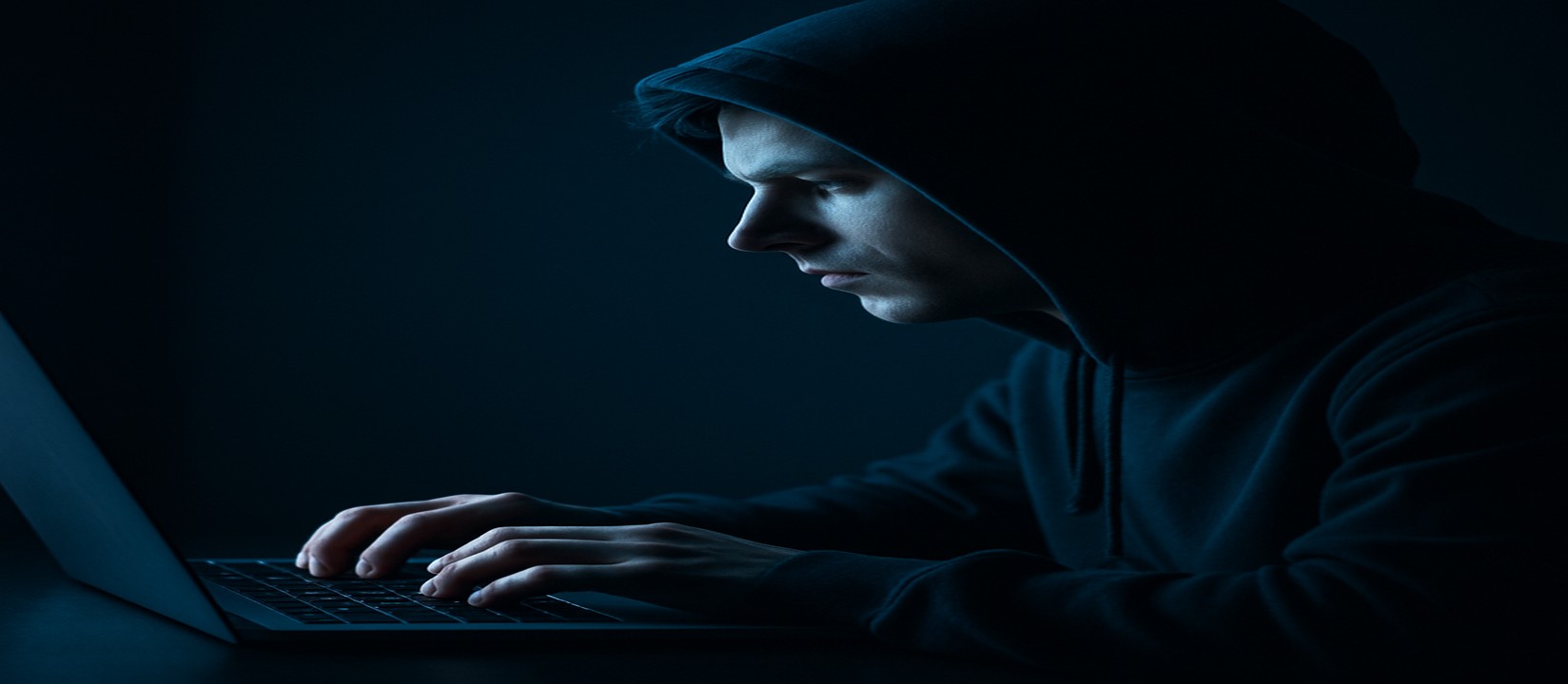 একজন ব্যক্তি অন্ধকার ঘরে ল্যাপটপে মনোযোগ দিয়ে 555w ওয়েবসাইটে অনলাইন গেমিং উপভোগ করছেন